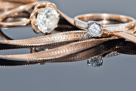 gold ring, earrings and chains on a reflective surfaceの写真素材