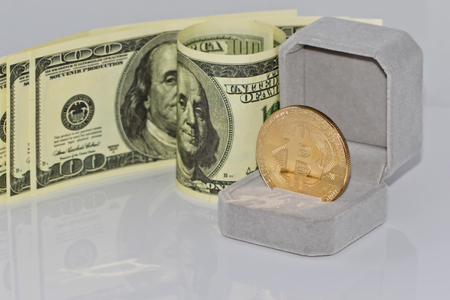 gold souvenir coin bitcoin lies in the gift box for jewelry on the background of dollarsの写真素材