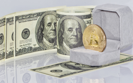 gold souvenir coin bitcoin lies in the gift box for jewelry on the background of dollarsの写真素材