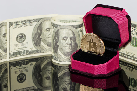 gold souvenir coin bitcoin lies in the gift box for jewelry on the background of dollarsの写真素材