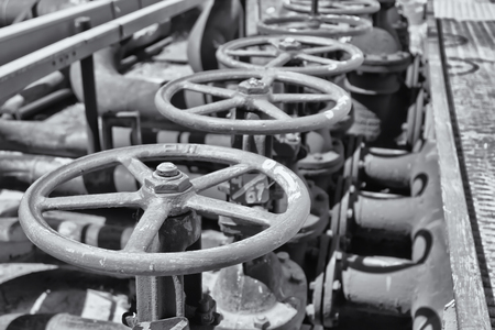 Worn steel catch on the old pipe in the workshop of a refinery with valve. Black and white photoの写真素材