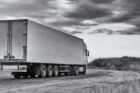 Big truck overtaking a small truck on a road in a rural landscapeの写真素材