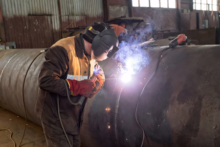 welder is repairing the defective area of the weld inside the parts of chemical apparatusの写真素材