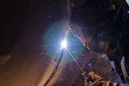 Welding works on the metal body of a large heat exchanger using manual arc welding. Close upの写真素材