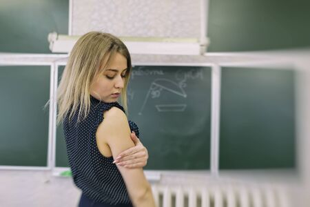 Young slim beautiful girl a blonde stay in classroom from back to the camera and dreamily closed her eyes の写真素材