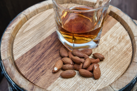 A small wooden oak barrel for home production of beer, cognac and whiskey and a glass of whiskey aged in itの写真素材