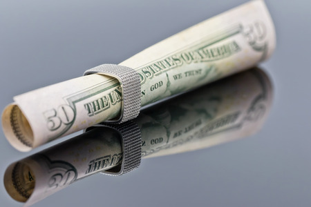 fifty dollar bill is rolled into a tube and inserted into an elegant women's silver ringの写真素材