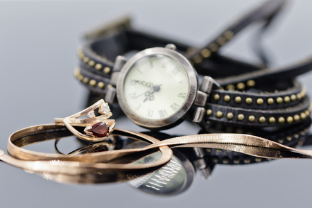 Elegant gold ring and chain lie on the background of women's watches with leather strapの写真素材