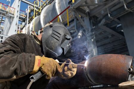 Welding works on the metal body of a large heat exchanger using manual arc welding. Close up
