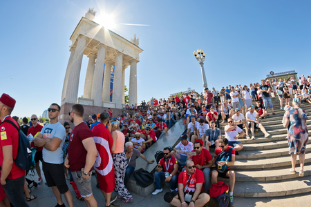 VOLGOGRAD - JUNE 18: Fans of England and Tunisia teams dressed in colors of national teams with flags and beer sit on steps of Central embankment and wait for match started. June 18, 2018 in Volgograd, Russia.のeditorial素材