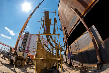 Repair work on replacement of the lower belts of the old rusty tank for storage of petroleum products with the use of cranesの写真素材