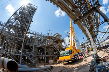A large hundred-ton truck crane with unfolded legs and extended boom stands on the construction site of the new petrochemical complex shopの写真素材