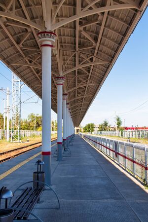 Long empty platform of suburban railway with benches and litter binsのeditorial素材