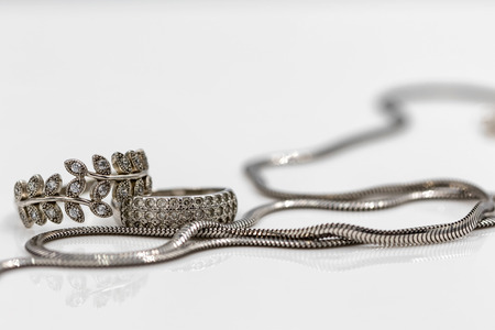 Elegant silver chain with snake weave and silver rings of classical shape and in the shape of a branch with leavesの写真素材