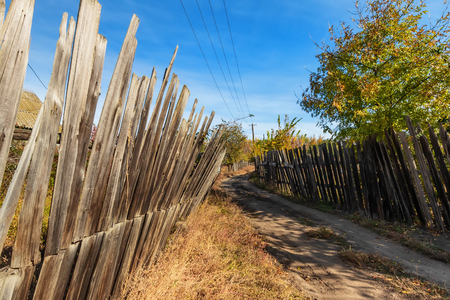Sketches from the life of a small Russian village. Rickety old wooden fences, small wooden houses and power line polesの写真素材