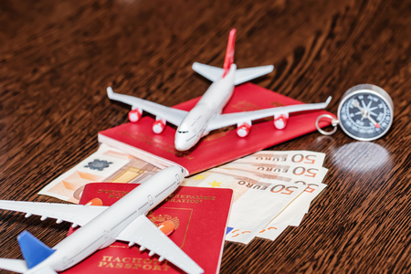 Passports, currency and toy airplanes are on the tableの写真素材