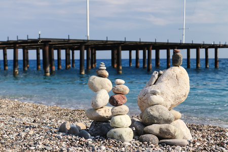 Sea stones of different sizes are built in a pyramid and keep balance. Coastal shoreline with views of the sea and pebble beachの写真素材