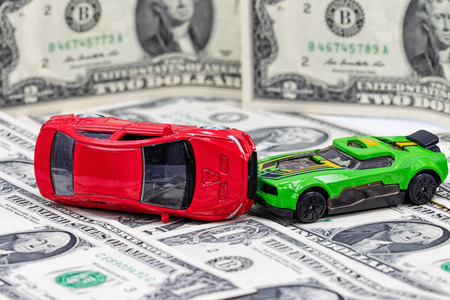 Accident between two toy cars on the background of dollar billsの写真素材