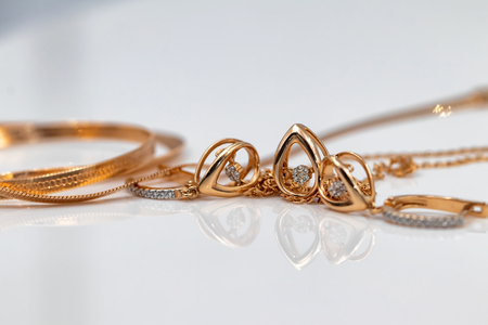 a set of gold earrings and pendants in the form of drops on a white surfaceの写真素材