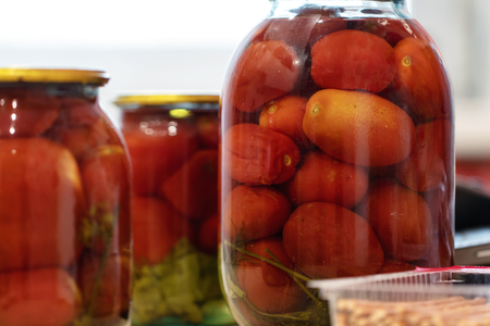 Canned salted tomatoes in cans are on the kitchen tableの写真素材