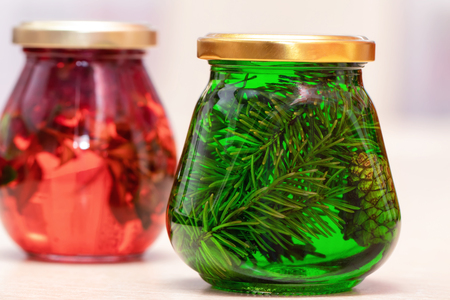 Jam of fir twigs and cones and mountain cranberries in small jars on the kitchen tableの写真素材