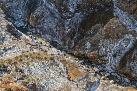 The view from the top of the cliff down into a ravine, through which flows a mountain river in winterの写真素材