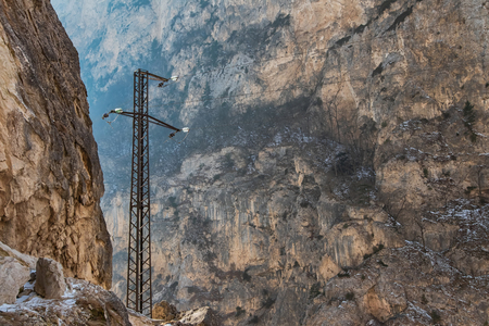 The poles of the power line laid in a mountainous area at high altitude against the mountain slopesの写真素材