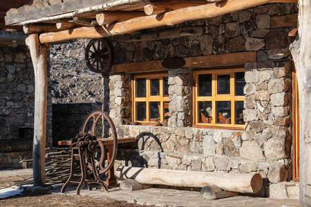 Restored Balkar hut made of large stones and wood with wool processing machine on the porchの写真素材