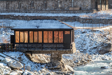 The building is a small cafe located in a mountainous area. The construction partially hangs over the bed of a small mountain riverの写真素材