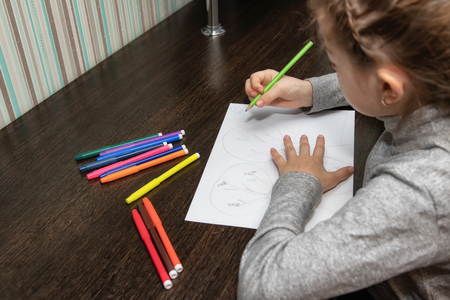 A student of Junior classes sitting at home at the table doing homework on drawingの写真素材