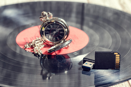 Compact electronic USB and SD drives lie on a vinyl recordの写真素材