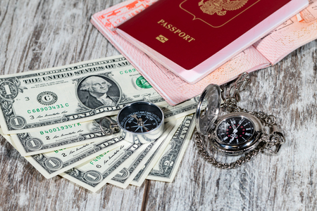 International passports, paper currency, pocket watches and a compass lie on a wooden tableの写真素材