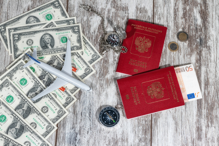 International passports, paper currency, pocket watches and a compass lie on a wooden tableの写真素材
