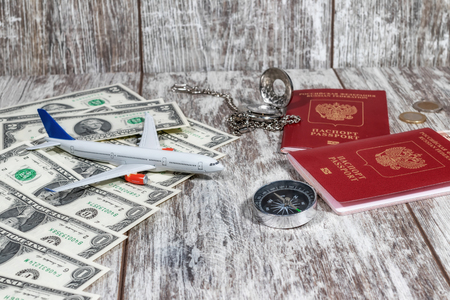 International passports, paper currency, pocket watches and a compass lie on a wooden tableの写真素材