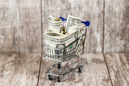 The cart from the supermarket is filled to the top with dollar billsの写真素材