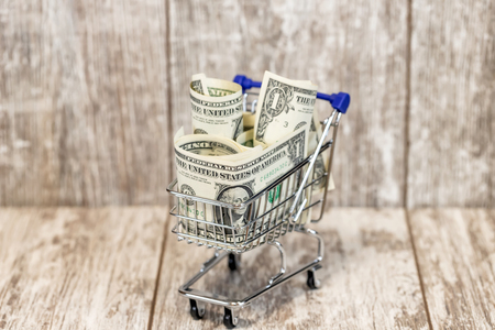 The cart from the supermarket is filled to the top with dollar billsの写真素材