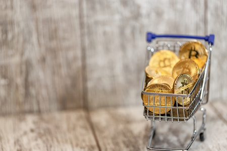 A metal toy cart from the supermarket is filled to the top with gold coins bitcoinの写真素材