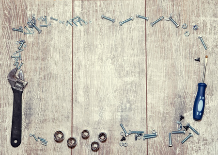 Layout for men's cards with a blank space for text on a wooden background and a frame of tools, bolts and nutsの写真素材