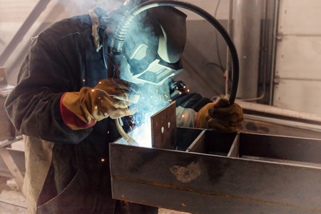 Welder performs welding work of metal structures in a complex spatial position semi-automatic...