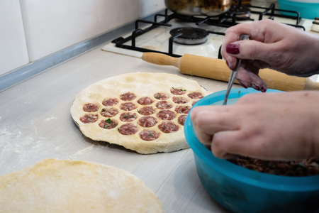 Laying minced meat on the dough in a special formの写真素材
