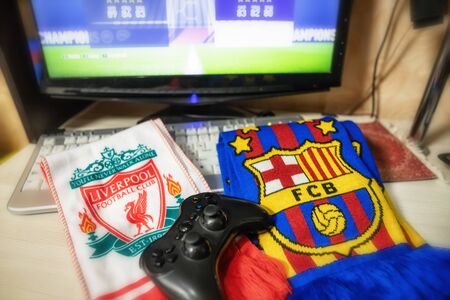 VOLGOGRAD - APRIL 25: Branded scarves football clubs Liverpool and Barcelona lie next to the table with the game joystick. April 25, 2019 in Volgograd, Russia.のeditorial素材