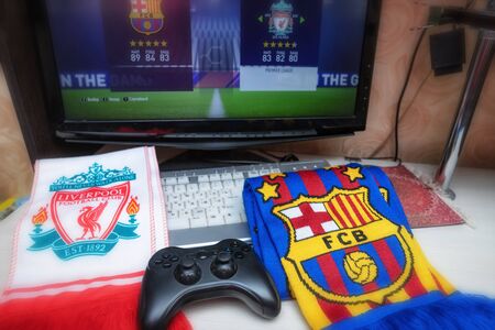 VOLGOGRAD - APRIL 25: Branded scarves football clubs Liverpool and Barcelona lie next to the table with the game joystick. April 25, 2019 in Volgograd, Russia.のeditorial素材