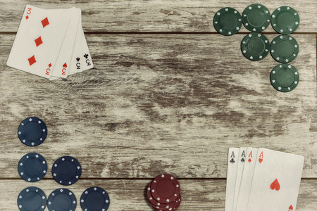 Casino playing chips and playing cards on a light wooden background are laid out on the edges with the ability to make an inscription in the center. The concept of gambling and casinosの写真素材