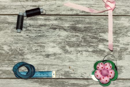 Buttons, ribbon , thread and needles for sewing . The concept of handmade sewing. On a light wooden backgroundの写真素材