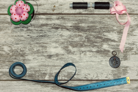 Buttons, ribbon , thread and needles for sewing . The concept of handmade sewing. On a light wooden backgroundの写真素材
