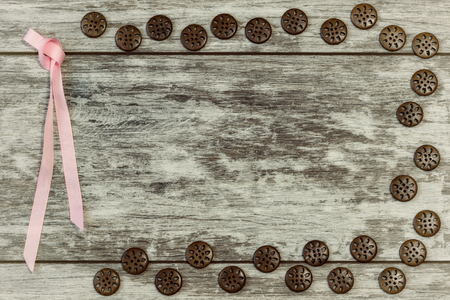 Buttons of different shapes and colors are laid out on a light wooden background at the edges with an empty space under the inscription in the center . The concept of handmade sewing.の写真素材