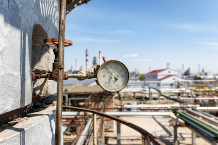 Old reliable pressure gauge mounted on a large column in an oil refineryの写真素材