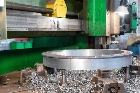 Old milling machine for machining large diameter parts by remote control. A large amount of metal chips lies next to the workpieceの写真素材