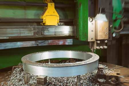 Old milling machine for machining large diameter parts by remote control. A large amount of metal chips lies next to the workpieceの写真素材