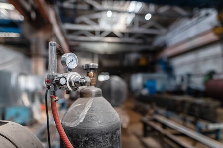 Old, dusty reducer and pressure gauge mounted on gas cylinder for welding in protective gas environmentの写真素材
